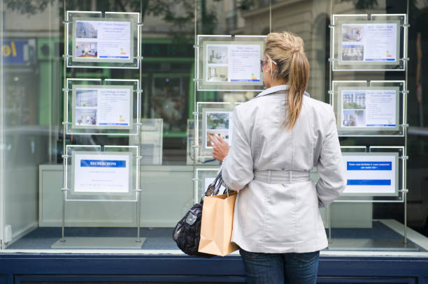 Femme qui regarde la vitrine d'une agence immobilière